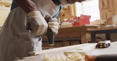 Afrika kökenli Amerikalı erkek marangoz el matkabı kullanarak tahta kalaslarda delik açıyor. Marangozluk, işçilik ve el işi konsepti