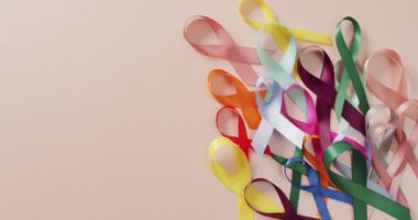 Video of colourful cancer ribbons on pale pink background. medical awareness support campaign symbols for various cancers.