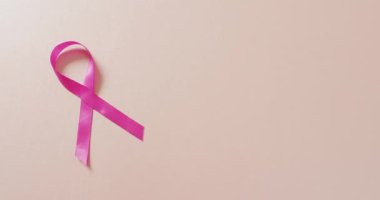 Video of pink breast cancer ribbon on pale pink background. medical awareness support campaign symbol for breast cancer.