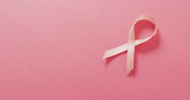 Video of pink breast cancer ribbon on pale pink background. medical awareness support campaign symbol for breast cancer.