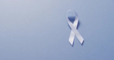 Video of pale blue prostate cancer ribbon on blue background. medical and healthcare awareness support campaign symbol for prostate cancer.