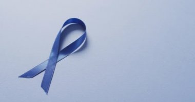 Video of dark blue colon cancer ribbon on pale blue background. medical and healthcare awareness support campaign symbol for colon cancer.