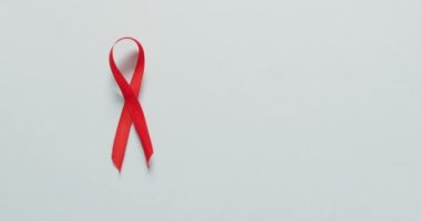 Video of red blood cancer ribbon on pale blue background. medical and healthcare awareness support campaign symbol for blood cancer.