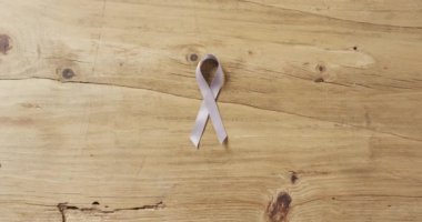 Video of white lung cancer ribbon on pale pink background. medical awareness support campaign symbol for lung cancer.