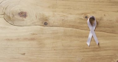 Video of white lung cancer ribbon on wooden background. medical awareness support campaign symbol for lung cancer.