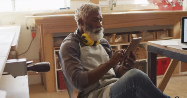 African American Male Carpenter Using Digital Tablet Sitting Carpentry Shop — Stok video
