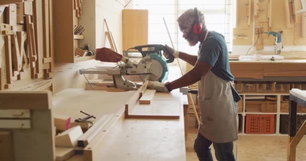 African American Male Carpenter Cutting Wooden Plank Electric Chop Saw — Vídeo de stock