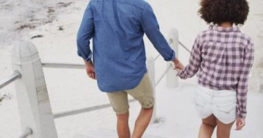 Sahilin yakınındaki merdivenlerden el ele tutuşan Afro-Amerikan çifti. Aşk ve ilişki kavramı