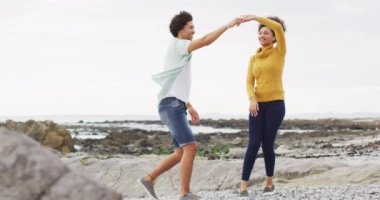 Afrika kökenli Amerikalı çift deniz kenarındaki kayalıklarda dans ediyor. Aşk ve ilişki kavramı