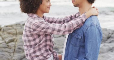 Afrika kökenli Amerikalı çift deniz kenarındaki kayalıklarda birbirini kucaklıyor. Aşk ve ilişki kavramı