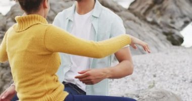 Afrika kökenli Amerikalı çift, deniz kenarındaki kayalıklarda oturup birbirlerine sarılıyorlar. Aşk ve ilişki kavramı