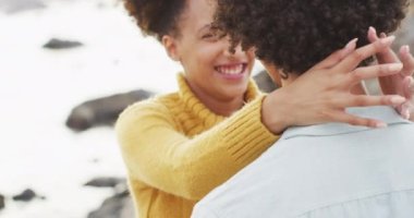 Deniz kenarındaki kayalıklarda birbirini kucaklayan Afrikalı Amerikalı çifti yakından takip edin. Aşk ve ilişki kavramı