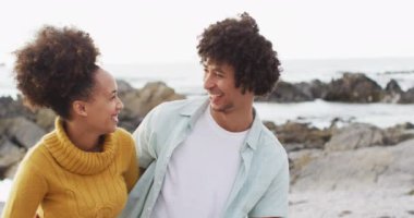 Denizin kenarındaki kayalıklarda gülümseyen Afrikalı Amerikalı bir çiftin portresi. Aşk ve ilişki kavramı