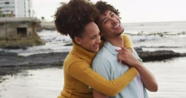 Deniz kenarındaki kayalıklarda birbirini kucaklayan Afrikalı Amerikalı çifti yakından takip edin. Aşk ve ilişki kavramı