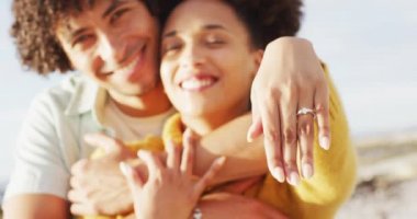 Yüzüklerini deniz kenarındaki kayalıklarda gösteren Afro-Amerikan çiftin portresi. Aşk ve ilişki kavramı