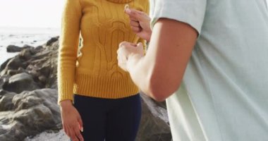 Afrika kökenli Amerikalı bir adam deniz kenarında kayalıklarda yüzükle kız arkadaşına evlenme teklif ediyor. Aşk ve ilişki kavramı