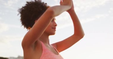 Afrika kökenli Amerikalı kadın yoga yapıyor ve deniz kenarındaki kayalıklarda meditasyon yapıyor. sağlıklı yaşam tarzı ve yaşam konsepti