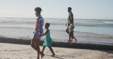 Sahilde el ele tutuşan Afrikalı Amerikalı bir aile. Aile seyahati ve tatil konsepti