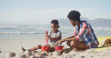 Afrika kökenli Amerikalı anne ve oğlu kumsalda oynuyorlar. Aile seyahati ve tatil konsepti