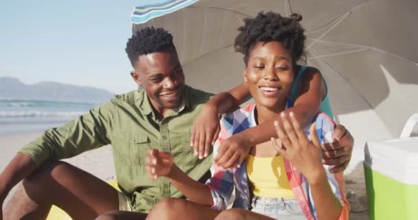 Familia Afroamericana Sonriendo Mientras Está Sentada Bajo Paraguas Playa Viajes — Vídeos de Stock