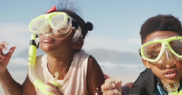 アフリカ系アメリカ人の兄と妹は ビーチでシュノーケリングをしたスキューバダイビングマスクをしています 家族旅行や休暇のコンセプト — ストック動画