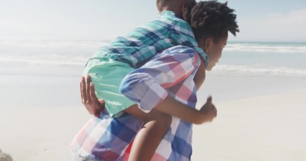 African American Mother Giving Piggyback Ride Her Son Beach Family — Stock Video