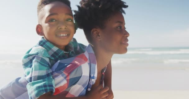 African American Mother Giving Piggyback Ride Her Son Beach Family — Stock Video
