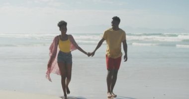 Sahilde yürürken gülümseyen Afrikalı Amerikalı çift. Aile seyahati ve tatil konsepti