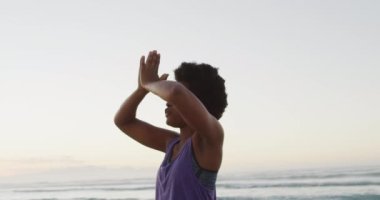 Afrika kökenli Amerikalı kadın güneşli sahilde yoga ve meditasyon yapıyor. sağlıklı ve aktif zaman plaj tatili.
