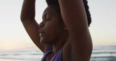Afrika kökenli Amerikalı kadın güneşli sahilde yoga ve meditasyon yapıyor. sağlıklı ve aktif zaman plaj tatili.