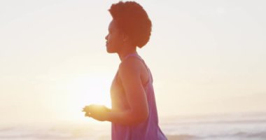 Mutlu Afro-Amerikan kadın güneşli sahilde yoga yapıyor. sağlıklı ve aktif zaman plaj tatili.