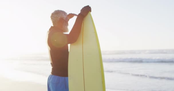 Hombre Afroamericano Mayor Sosteniendo Tabla Surf Playa Soleada Tiempo Saludable — Vídeos de Stock