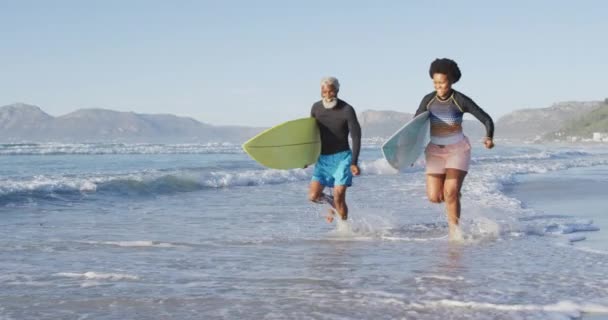 Glad Afrikansk Amerikansk Par Kör Med Surfbrädor Solig Strand Hälsosam — Stockvideo