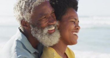 Mutlu Afro-Amerikan çifti güneşli sahilde oturup kucaklaşıyor. sağlıklı ve aktif zaman plaj tatili.