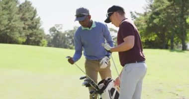 Golf sahasında para ödemek için golf sopaları hazırlayan çeşitli erkek arkadaşların videosu. spor, aktif yaşam tarzı ve golf konsepti.