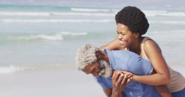 Mutlu Afro-Amerikan çifti güneşli sahilde yürüyor ve kucaklaşıyor. sağlıklı ve aktif zaman plaj tatili.