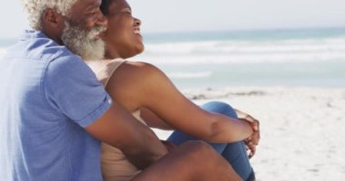 Mutlu Afro-Amerikan çifti güneşli sahilde oturup kucaklaşıyor. sağlıklı ve aktif zaman plaj tatili.