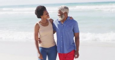 Mutlu Afro-Amerikan çifti güneşli sahilde yürüyor ve kucaklaşıyor. sağlıklı ve aktif zaman plaj tatili.
