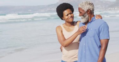 Mutlu Afro-Amerikan çifti güneşli sahilde yürüyor ve kucaklaşıyor. sağlıklı ve aktif zaman plaj tatili.