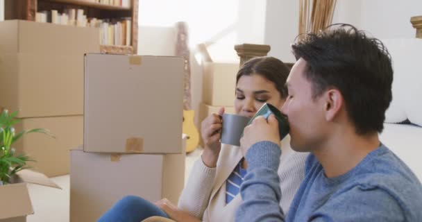 引越し後の新しい家の中で多様な夫婦がコーヒーを飲んでいる様子を動画 新しい人生を共に始め — ストック動画