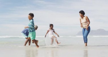 Mutlu Afro-Amerikan çifti güneşli sahilde çocuklarla oynuyor. sağlıklı ve aktif zaman plaj tatili.