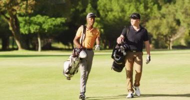 Farklı erkek arkadaşların golf sahasında yürüdüğü bir video. spor, aktif yaşam tarzı ve golf konsepti.