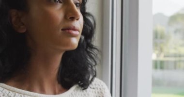 Pencereden bakıp gülümseyen mutlu melez kadın. evde yalnız zaman geçirmek..