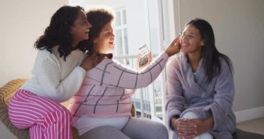 Mutlu çeşitli bayan arkadaşlar makyaj yapıyor ve yatak odasında gülümsüyor. evde kaliteli zaman geçirmek. 