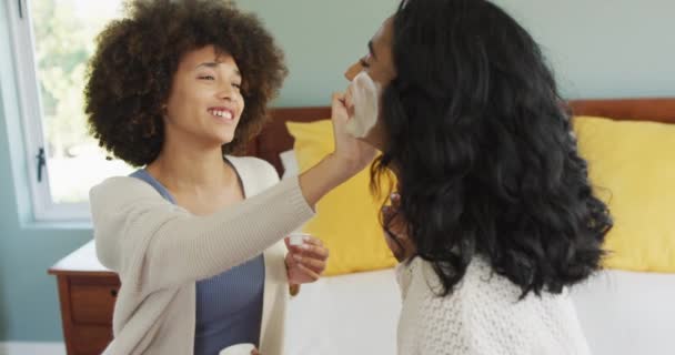 Glada Olika Kvinnliga Vänner Sitter Sängen Och Tillämpa Skönhet Ansiktsmask — Stockvideo