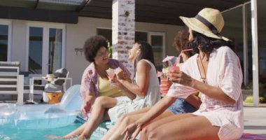 Yüzme havuzu partisinde konuşan ve gülümseyen çeşitli bayan arkadaşların kutlu olsun. evde kaliteli zaman geçirmek.