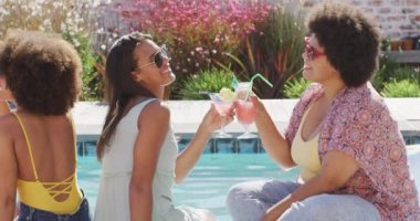 Mutlu çeşitli bayan arkadaşlar yüzme havuzunda tost yapıyor ve gülümsüyor. evde kaliteli zaman geçirmek.