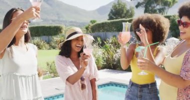 Mutlu çeşitli bayan arkadaşlar yüzme havuzunda tost yapıyor ve gülümsüyor. evde kaliteli zaman geçirmek.