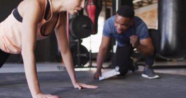 Afrikalı Amerikalı erkek eğitmenin beyaz kadını şınav çekmeye motive ettiği bir video. aktif, formda, sportif ve sağlıklı yaşam tarzı, spor konsepti egzersizi.