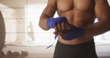 Orta bölüm Afro-Amerikan bir adamın spor salonunda boks antrenmanına hazırlandığı video. aktif, formda, sportif ve sağlıklı yaşam tarzı, spor konsepti egzersizi.